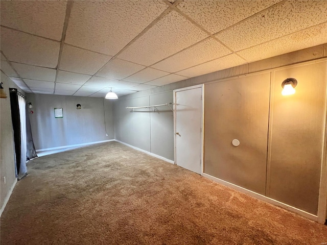 basement featuring a drop ceiling and carpet