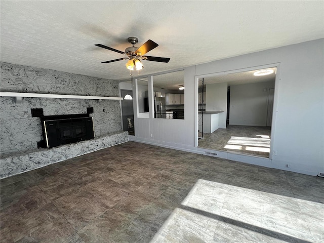 unfurnished living room with a premium fireplace, ceiling fan, and a textured ceiling