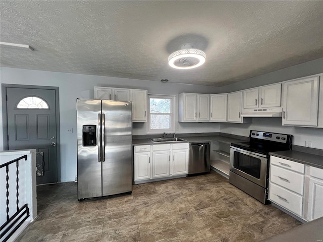 kitchen with appliances with stainless steel finishes, sink, a textured ceiling, and white cabinets