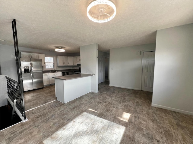 kitchen with sink, kitchen peninsula, a textured ceiling, and stainless steel refrigerator with ice dispenser