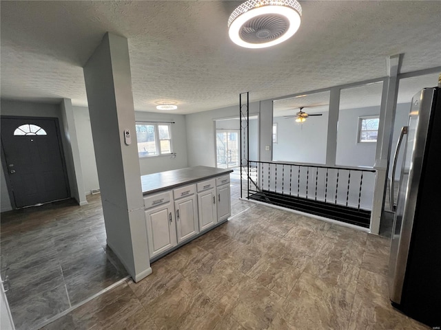 kitchen featuring white cabinetry, stainless steel fridge, and a textured ceiling