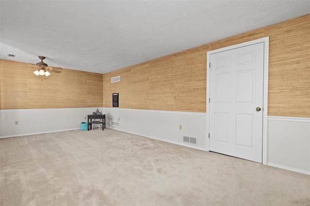 empty room featuring ceiling fan, light colored carpet, and a textured ceiling