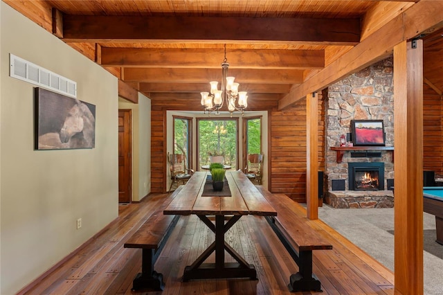 dining space featuring a fireplace, a notable chandelier, hardwood / wood-style floors, beamed ceiling, and wood ceiling