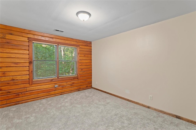 empty room with light carpet and wooden walls