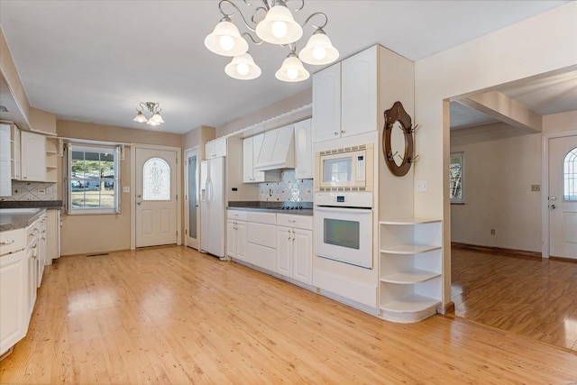 kitchen with premium range hood, pendant lighting, white cabinetry, light wood-type flooring, and white appliances