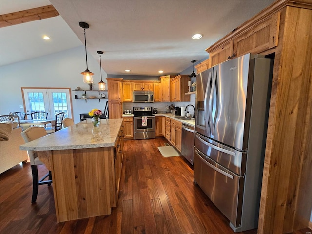 kitchen featuring pendant lighting, sink, appliances with stainless steel finishes, a kitchen breakfast bar, and light stone counters