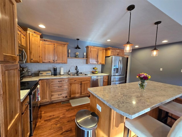 kitchen featuring pendant lighting, sink, dark wood-type flooring, a breakfast bar, and stainless steel appliances