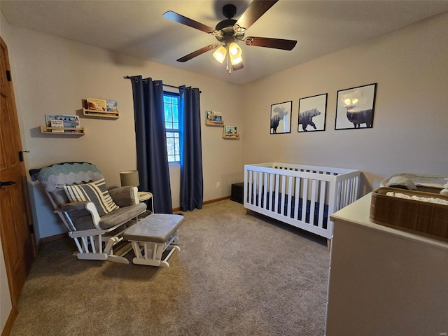 carpeted bedroom featuring a nursery area and ceiling fan