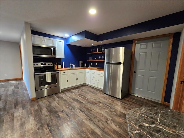 kitchen featuring sink, appliances with stainless steel finishes, dark hardwood / wood-style floors, white cabinets, and wood counters