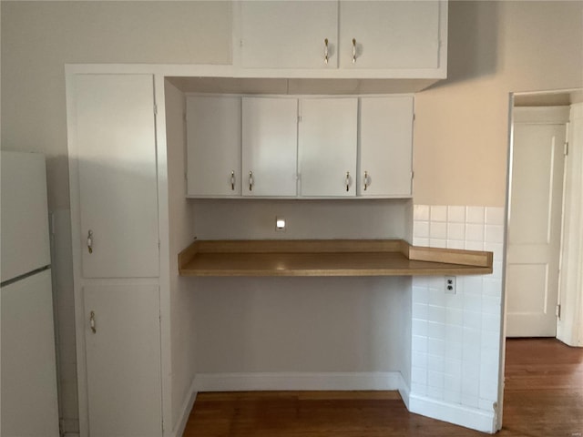 kitchen with white cabinetry, dark hardwood / wood-style flooring, white fridge, and tile walls