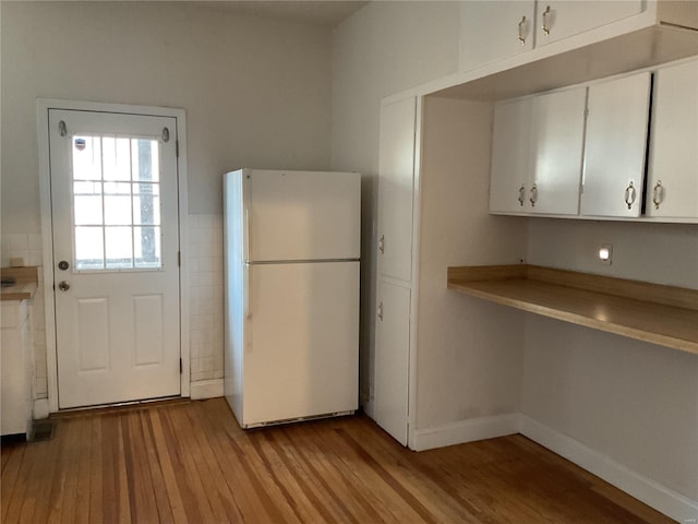 kitchen featuring light wood-type flooring, white cabinets, and white fridge