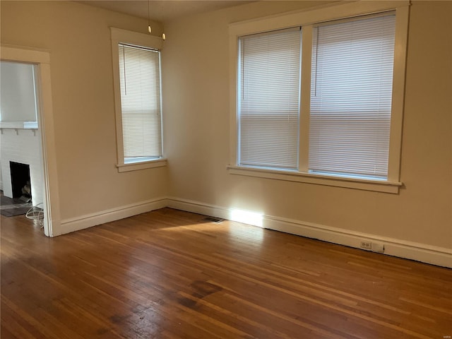 empty room featuring hardwood / wood-style flooring and a brick fireplace