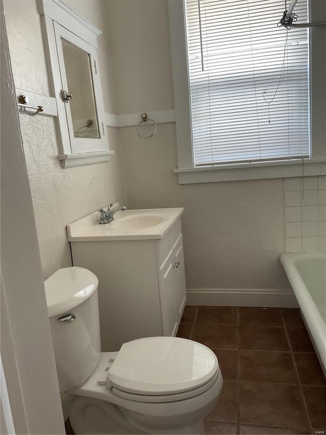 bathroom with a washtub, vanity, tile patterned floors, and toilet