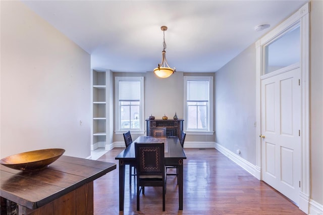 dining room with built in shelves and hardwood / wood-style floors