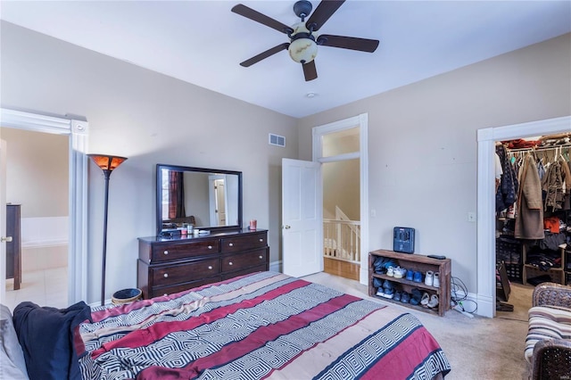 carpeted bedroom with a spacious closet, a closet, connected bathroom, and ceiling fan