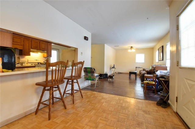 kitchen featuring refrigerator, range, a kitchen bar, and light parquet flooring