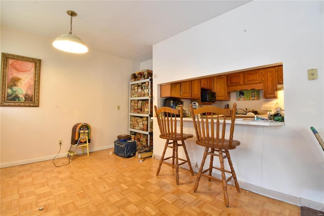 kitchen featuring a kitchen bar, light parquet flooring, pendant lighting, and kitchen peninsula