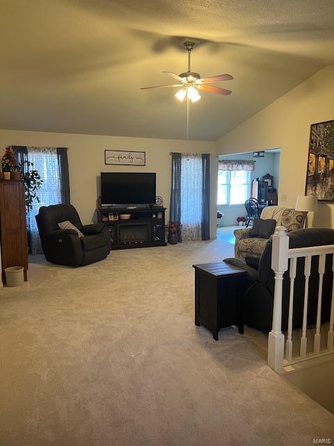 living room featuring vaulted ceiling, ceiling fan, carpet floors, and a textured ceiling