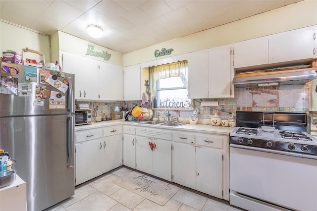 kitchen with tasteful backsplash, white cabinetry, sink, stainless steel fridge, and white range with gas cooktop