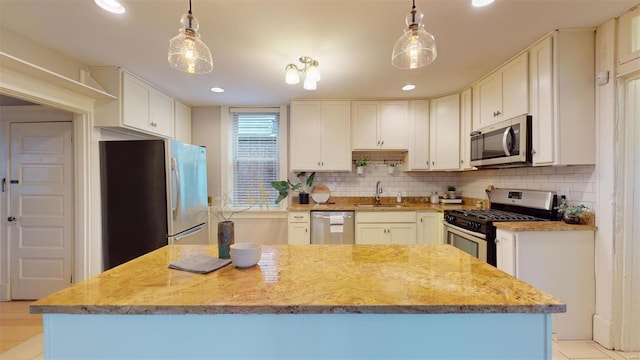 kitchen with hanging light fixtures, appliances with stainless steel finishes, sink, and white cabinetry