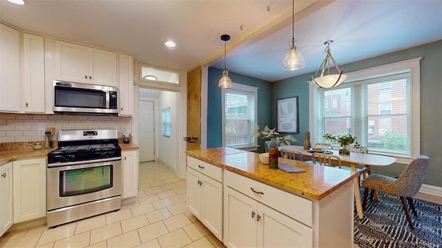 kitchen featuring appliances with stainless steel finishes, pendant lighting, decorative backsplash, and white cabinets