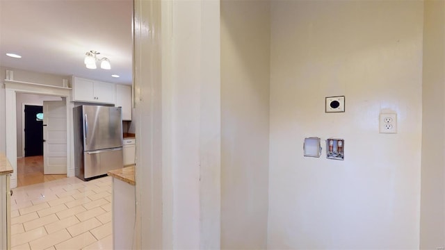 kitchen featuring light tile patterned floors, stainless steel refrigerator, and white cabinetry