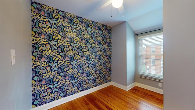 empty room featuring hardwood / wood-style flooring, ceiling fan, and vaulted ceiling