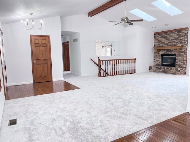 living room with a brick fireplace, vaulted ceiling with skylight, ceiling fan with notable chandelier, and wood-type flooring