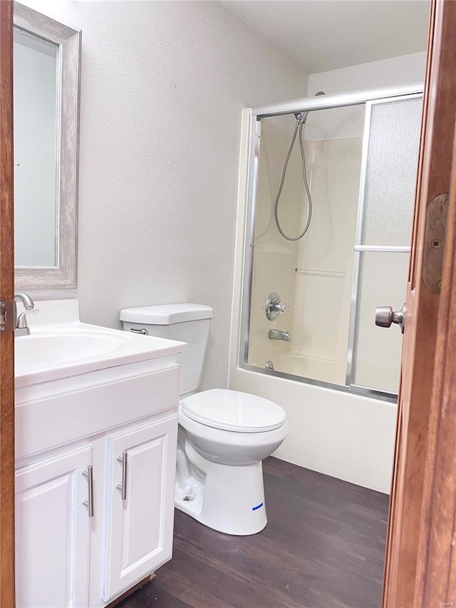 full bathroom with wood-type flooring, toilet, vanity, and shower / bath combination with glass door