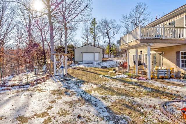 yard layered in snow featuring a deck, an outdoor structure, and a garage