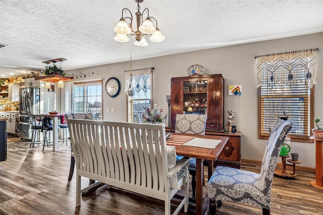 dining room with a textured ceiling, dark hardwood / wood-style flooring, and a chandelier