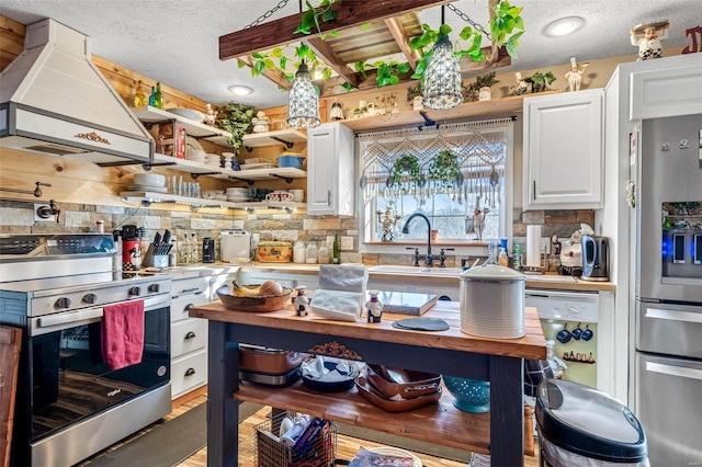 kitchen with a textured ceiling, appliances with stainless steel finishes, white cabinetry, sink, and custom range hood