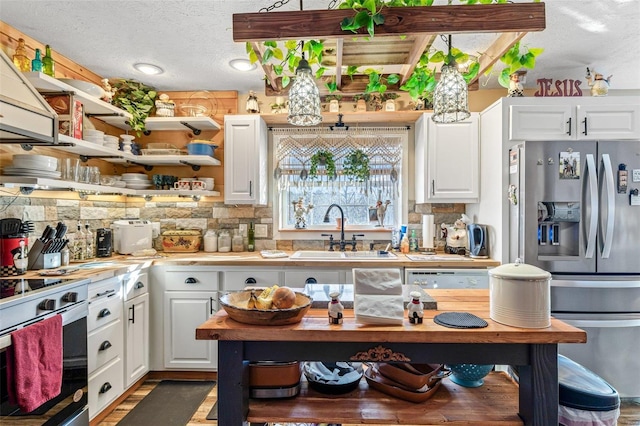 kitchen with a textured ceiling, white cabinetry, stainless steel appliances, sink, and backsplash