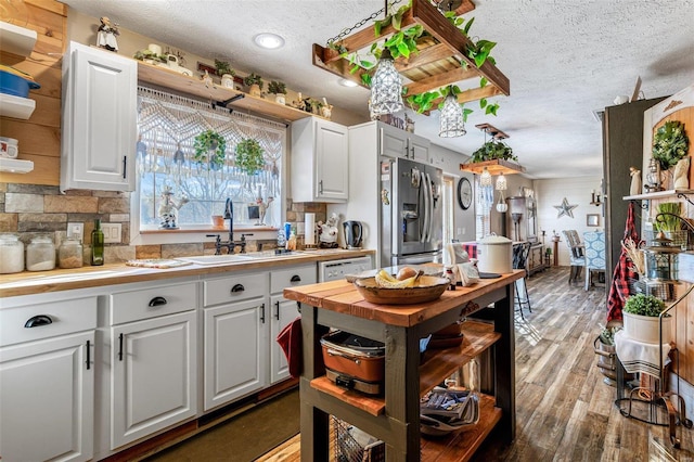 kitchen featuring a textured ceiling, white cabinets, wood-type flooring, sink, and stainless steel fridge