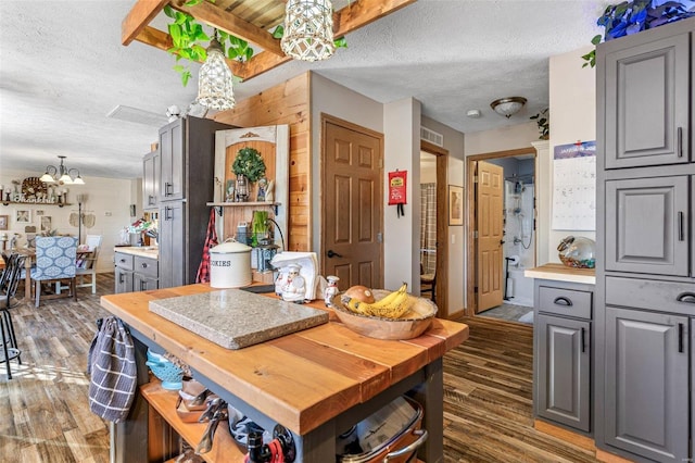 kitchen with a textured ceiling, decorative light fixtures, dark hardwood / wood-style floors, gray cabinets, and a chandelier