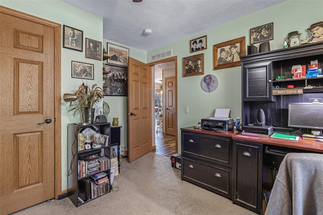 office area with a textured ceiling and light carpet