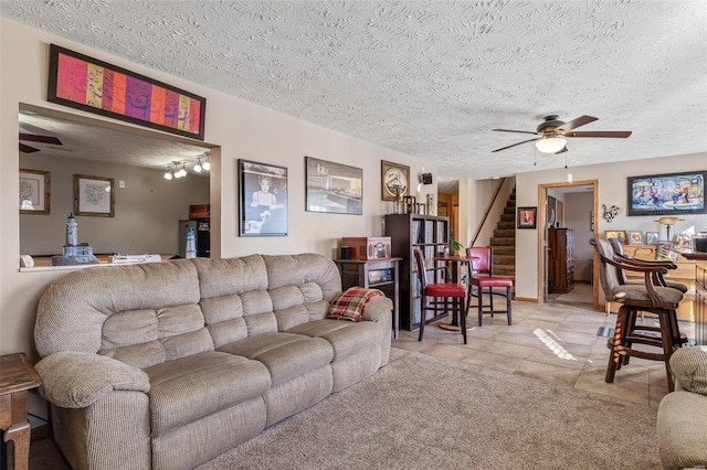 living room with a textured ceiling, ceiling fan, and light tile patterned flooring