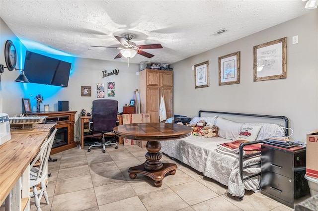 bedroom featuring ceiling fan, light tile patterned flooring, and a textured ceiling