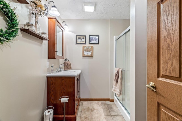 bathroom with an enclosed shower, vanity, and a textured ceiling