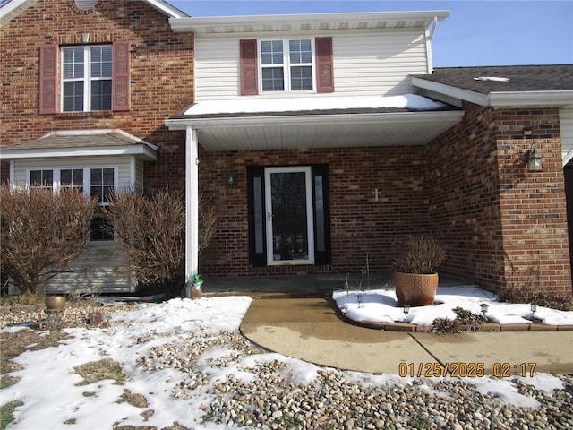 snow covered property entrance with covered porch