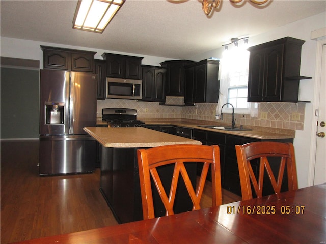 kitchen featuring appliances with stainless steel finishes, tasteful backsplash, sink, a center island, and dark wood-type flooring