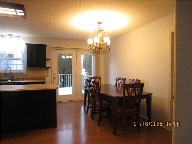 dining room featuring a healthy amount of sunlight, dark hardwood / wood-style flooring, a chandelier, and sink