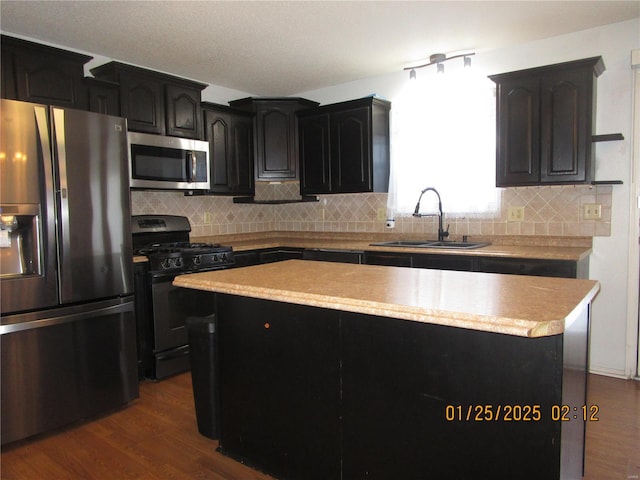 kitchen featuring sink, stainless steel appliances, dark hardwood / wood-style floors, a center island, and decorative backsplash