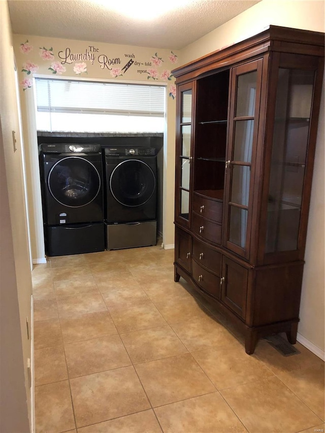 clothes washing area featuring independent washer and dryer, a textured ceiling, and light tile patterned floors