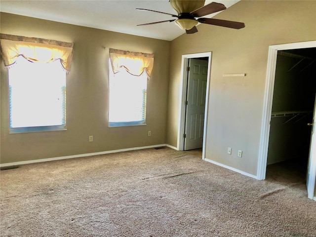 unfurnished bedroom featuring vaulted ceiling, a walk in closet, carpet, ceiling fan, and a closet