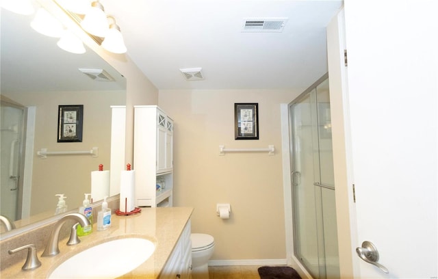 bathroom featuring toilet, a shower with shower door, and vanity