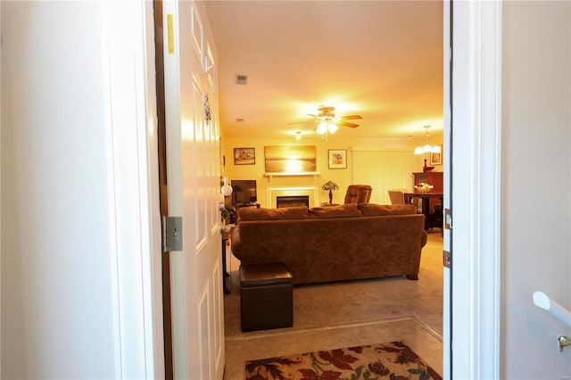 carpeted living room with ceiling fan with notable chandelier