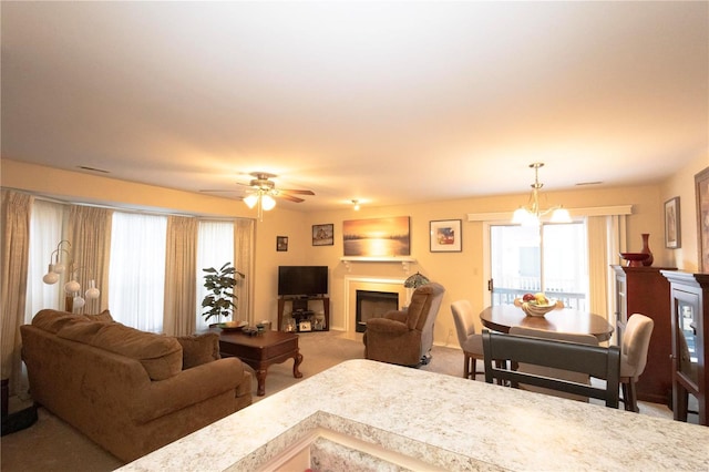 carpeted living room featuring ceiling fan with notable chandelier