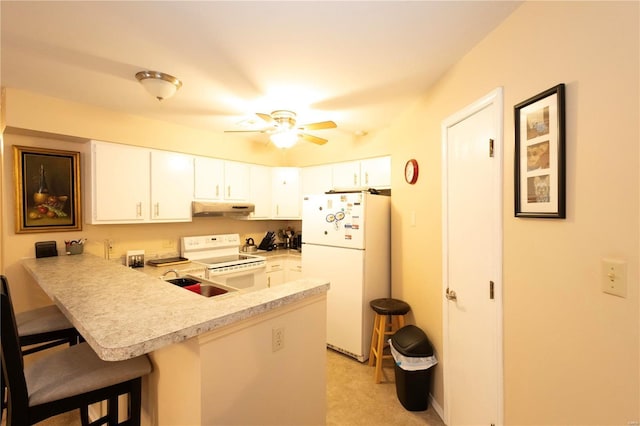 kitchen featuring white cabinets, white appliances, kitchen peninsula, and a breakfast bar area