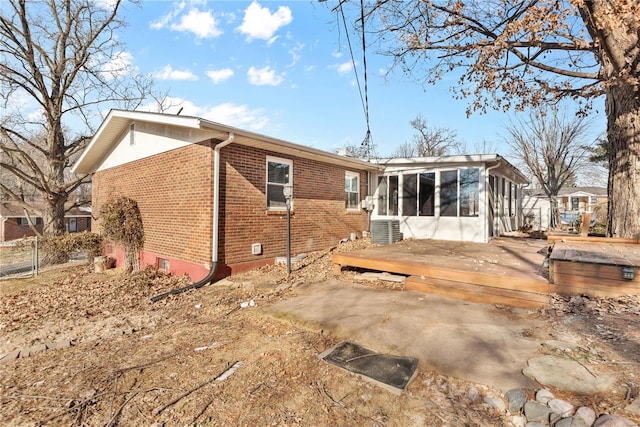 rear view of house with cooling unit, a wooden deck, and a sunroom